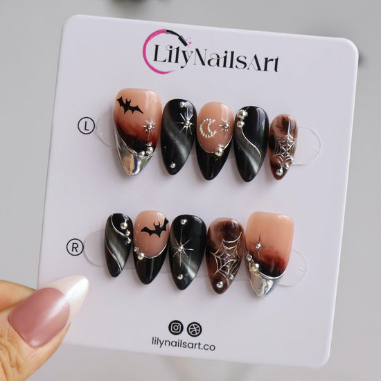 Batwing handmade gothic Halloween press-on nails — medium almond set in nude, black cat-eye and smoky brown with silver chrome tips, bats, rhinestone crescent moon and silver spiderwebs.