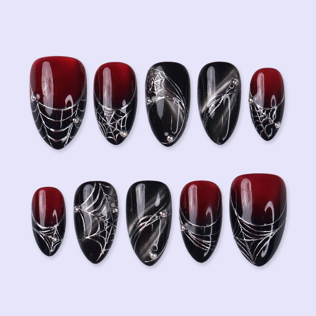 Arachne handmade gothic Halloween press-on nails — short almond set in blood-red and black cat-eye shimmer with silver spiderwebs and metallic bead accents.