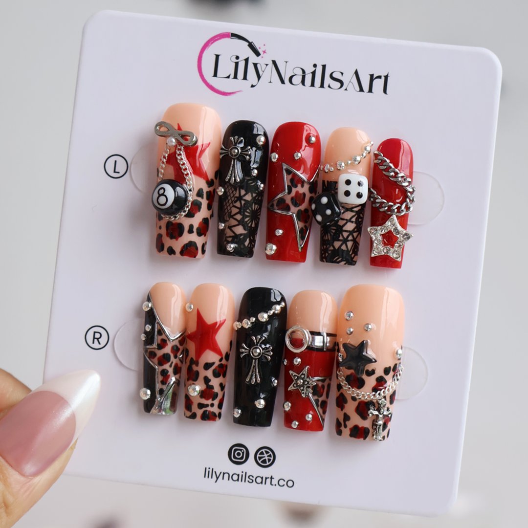 Lucky Riot handmade designer press-on nails — long square set in glossy red, black and nude with leopard print, stars, silver chains, eight ball, dice, metallic charms and rhinestone accents.