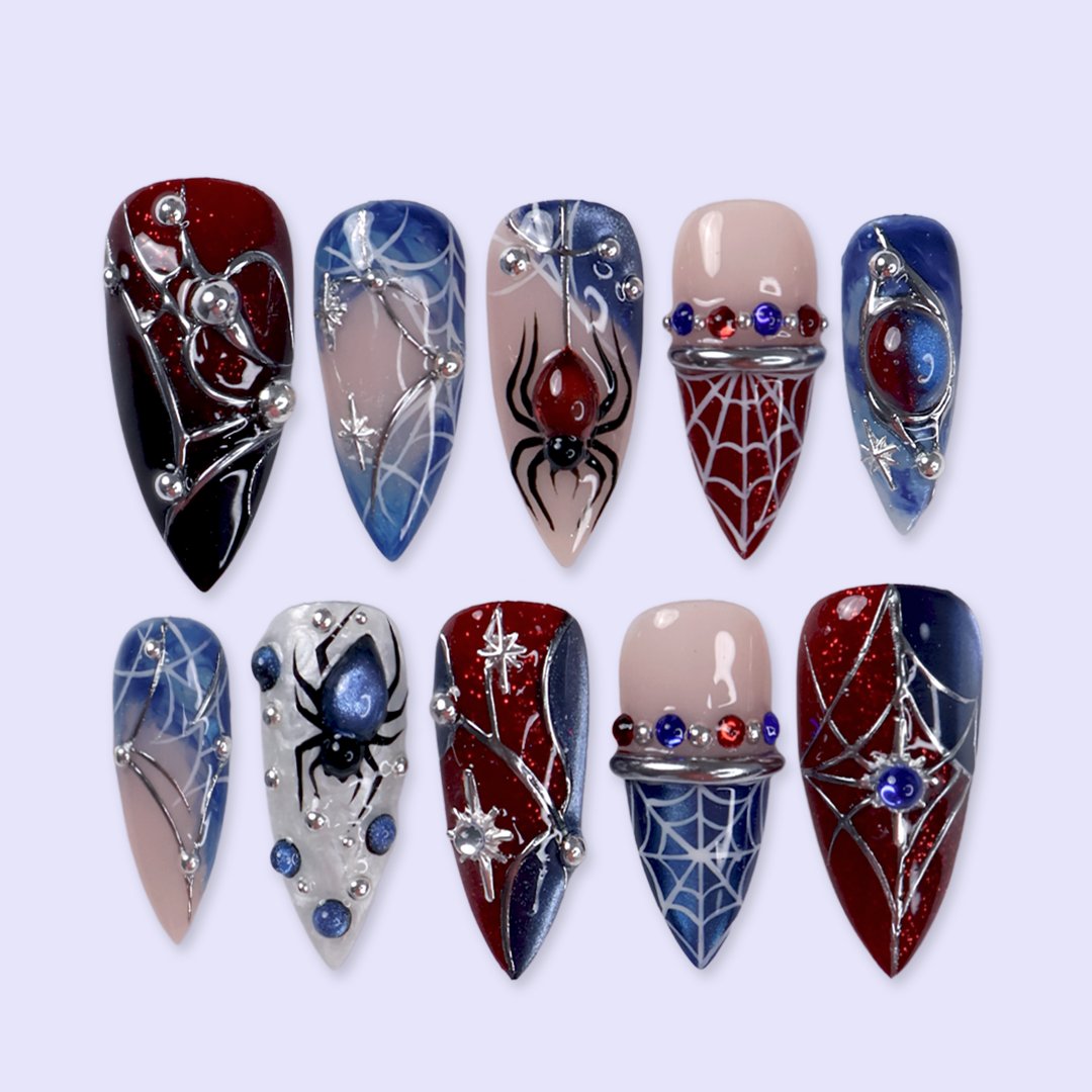 Arachnova handmade gothic Halloween press-on nails — medium stiletto set in blood-red, midnight blue, black and nude with 3D spiders, silver spiderwebs, celestial stars and jewel accents.