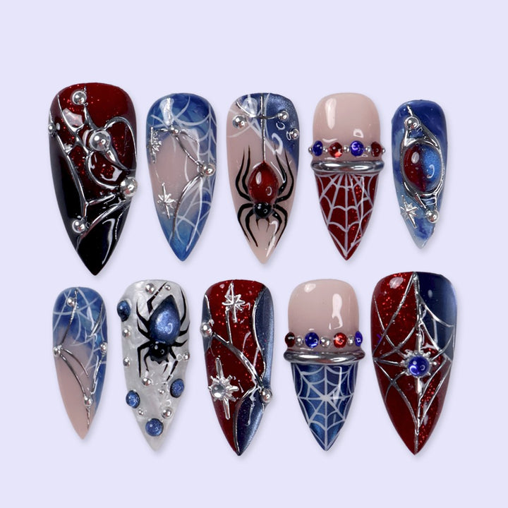 Arachnova handmade gothic Halloween press-on nails — medium stiletto set in blood-red, midnight blue, black and nude with 3D spiders, silver spiderwebs, celestial stars and jewel accents.