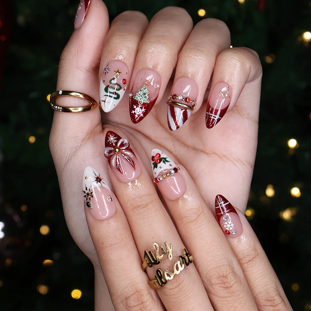 Jubilee handmade Christmas press-on nails — medium almond set in nude, red and cream with a glitter Christmas tree, snowflakes, red plaid, gold bow, holly berries, candy-cane stripes and gold star accents.