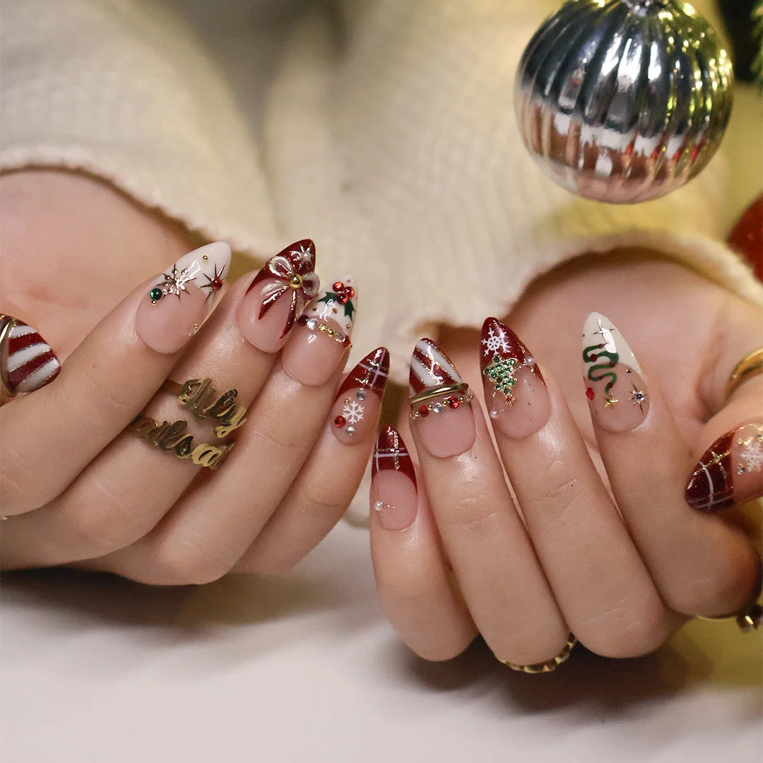Jubilee handmade Christmas press-on nails — medium almond set in nude, red and cream with a glitter Christmas tree, snowflakes, red plaid, gold bow, holly berries, candy-cane stripes and gold star accents.