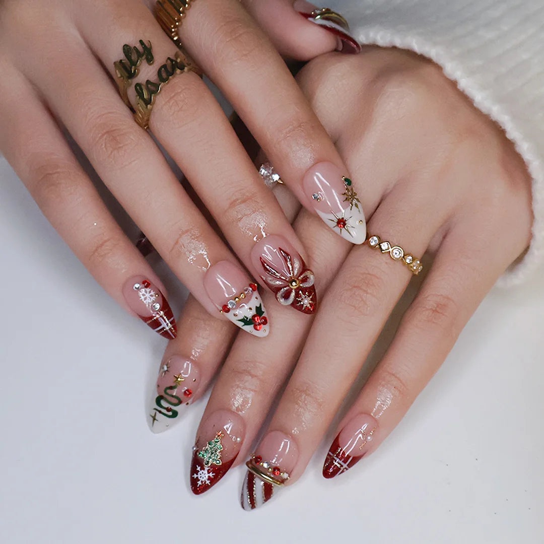 Jubilee handmade Christmas press-on nails — medium almond set in nude, red and cream with a glitter Christmas tree, snowflakes, red plaid, gold bow, holly berries, candy-cane stripes and gold star accents.