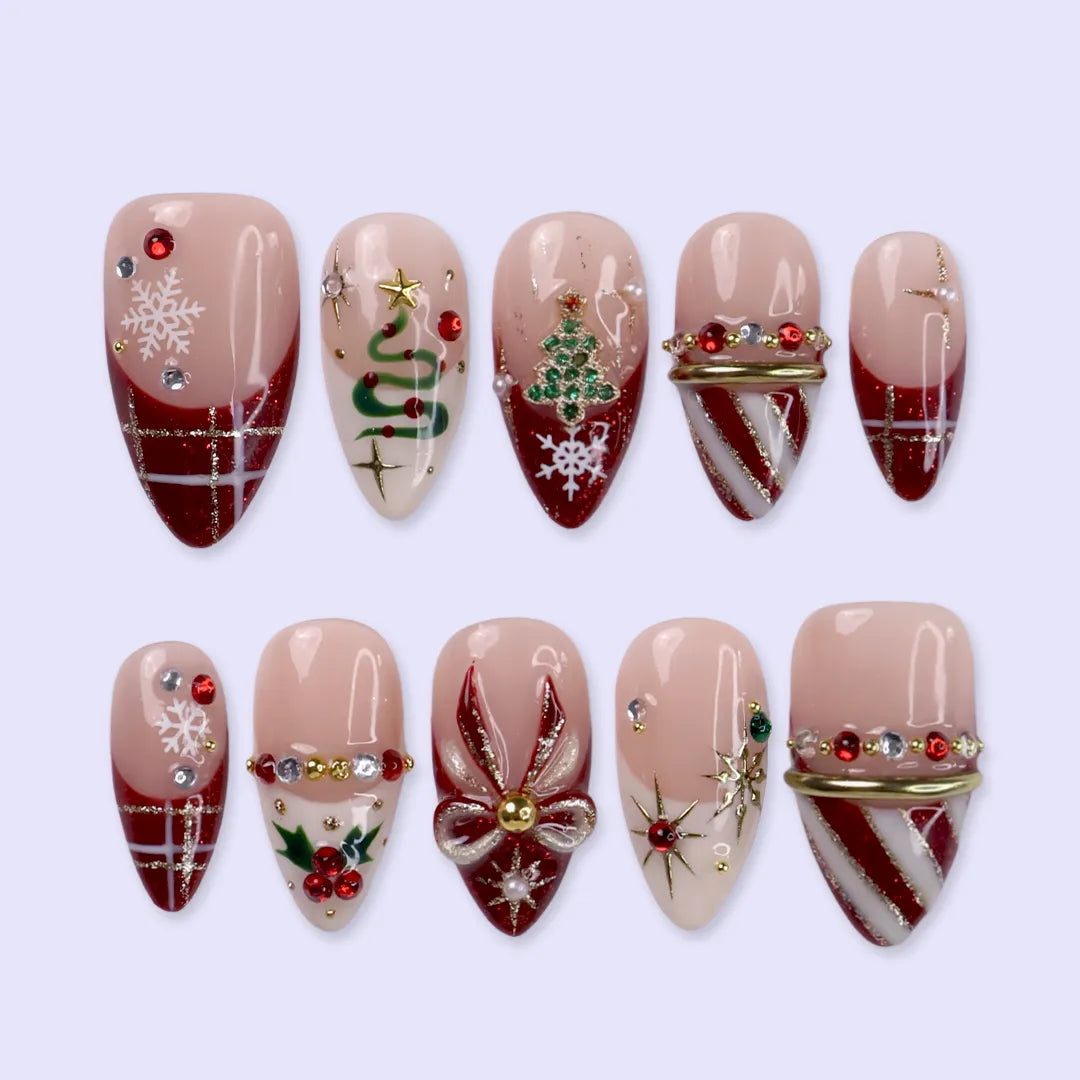 Jubilee handmade Christmas press-on nails — medium almond set in nude, red and cream with a glitter Christmas tree, snowflakes, red plaid, gold bow, holly berries, candy-cane stripes and gold star accents.