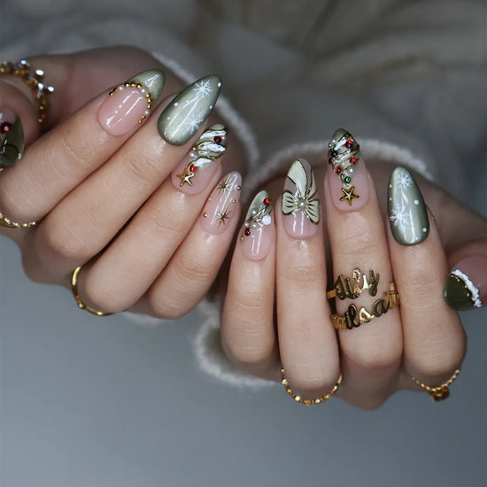 Wintergreen handmade Christmas press-on nails — medium almond set in nude and sage-green cat-eye with a 3D gold-star Christmas tree, delicate snowflakes, gold bow, ornament baubles and red-green gemstone accents.