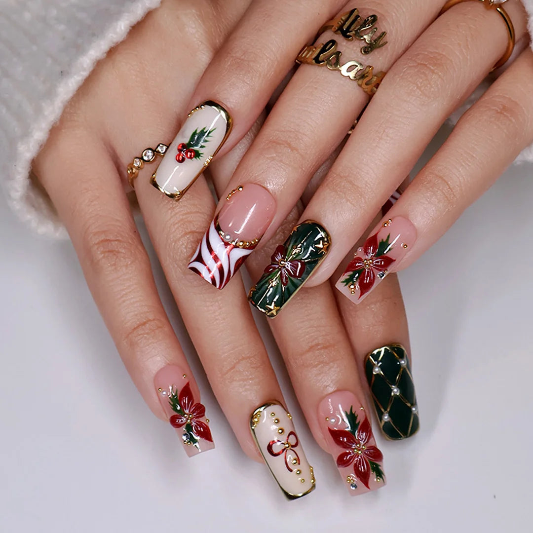 Yulamar handmade Christmas press-on nails — medium square set in nude, deep green and cream with 3D red poinsettias, red and gold bows, holly berries, candy-cane swirls, gold lattice details and pearl accents.
