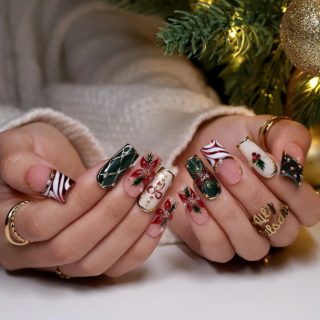 Yulamar handmade Christmas press-on nails — medium square set in nude, deep green and cream with 3D red poinsettias, red and gold bows, holly berries, candy-cane swirls, gold lattice details and pearl accents.