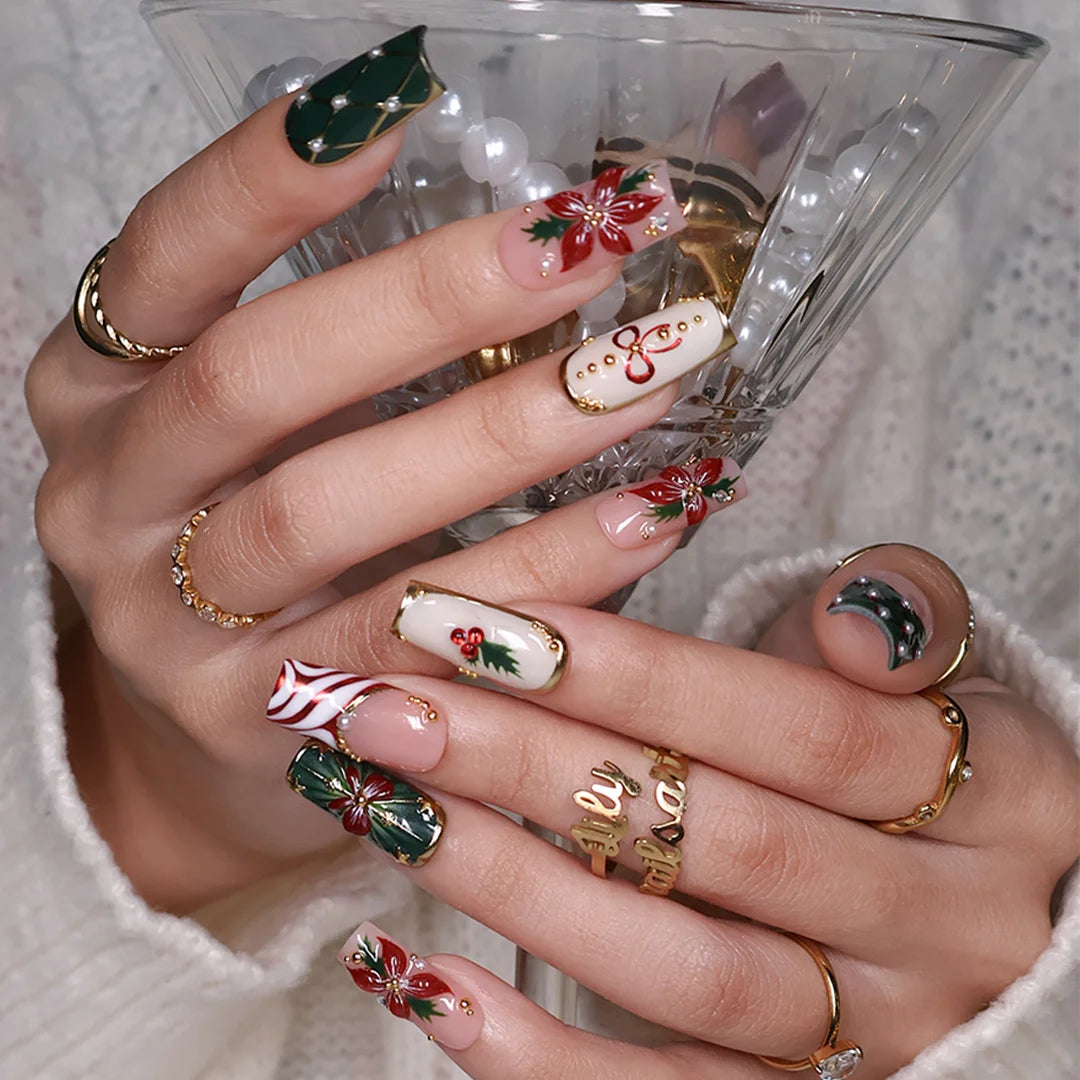 Yulamar handmade Christmas press-on nails — medium square set in nude, deep green and cream with 3D red poinsettias, red and gold bows, holly berries, candy-cane swirls, gold lattice details and pearl accents.