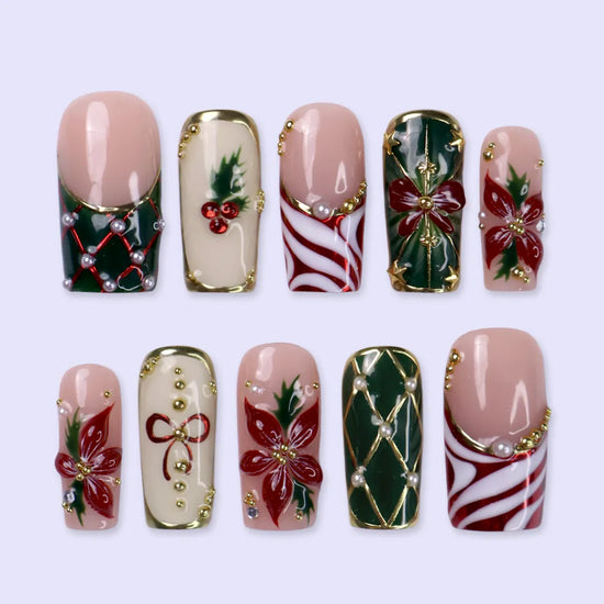 Yulamar handmade Christmas press-on nails — medium square set in nude, deep green and cream with 3D red poinsettias, red and gold bows, holly berries, candy-cane swirls, gold lattice details and pearl accents.