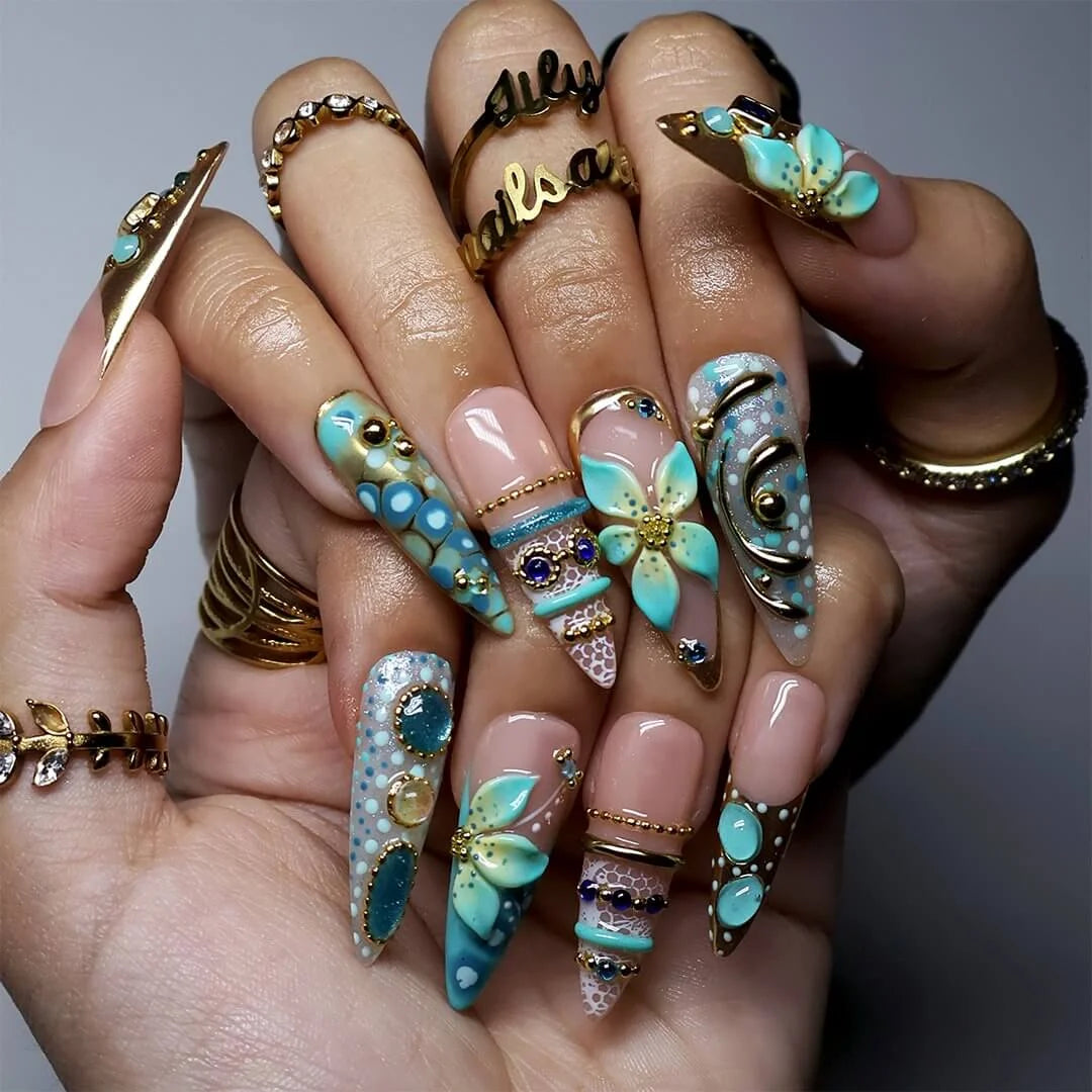 a hand model wearing Handmade summer press-on nails — maximalist long almond set  in tiffany blue with sapphire gems, gold filigree and aqua 3D lilies
