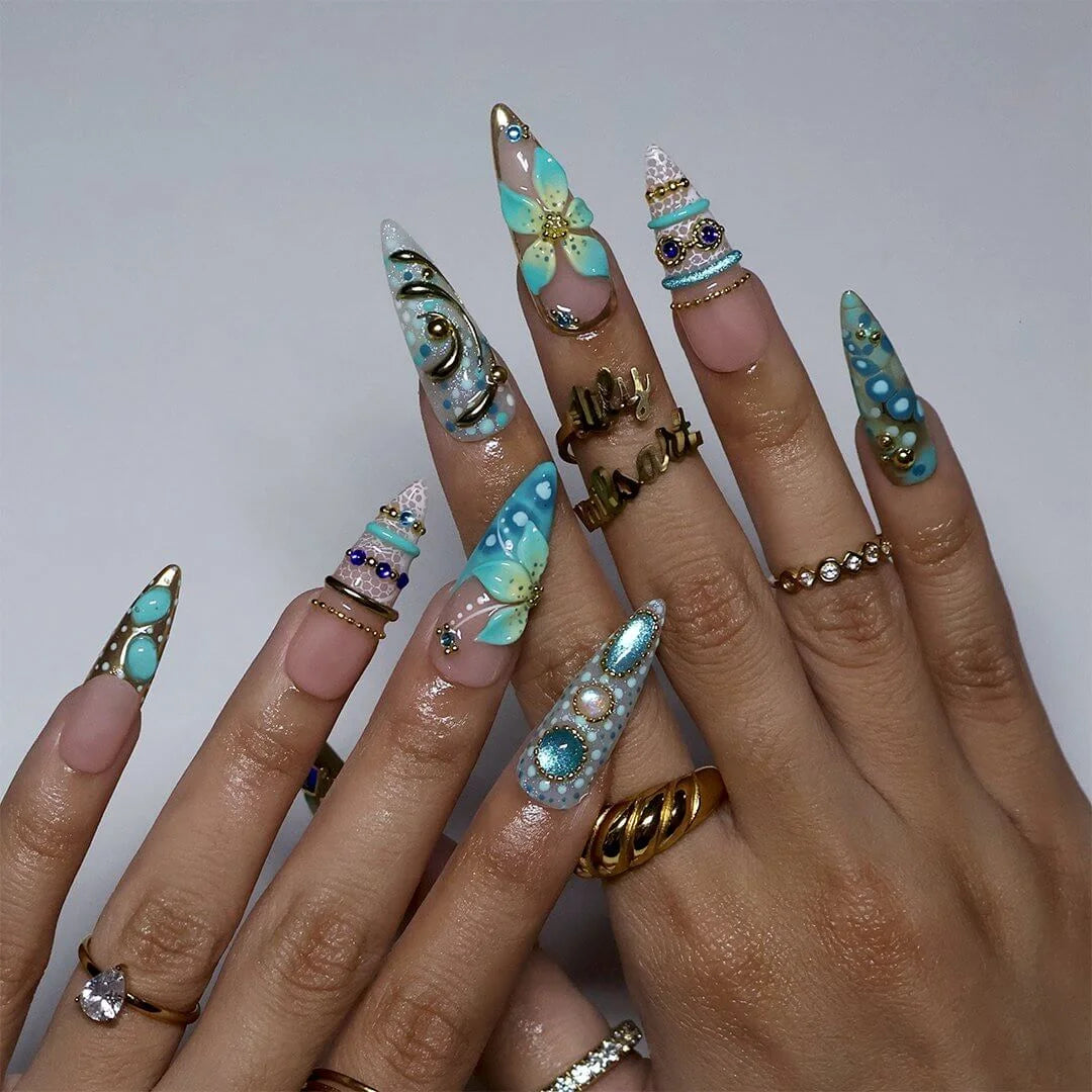 a hand model wearing Handmade summer press-on nails — maximalist long almond set  in tiffany blue with sapphire gems, gold filigree and aqua 3D lilies
