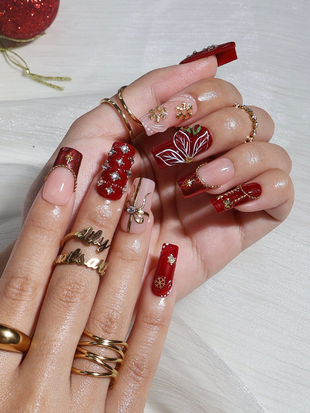 3D red & nude press on nails in medium square with christmas tree, gold charms, snowflakes, and poinsettia details — luxury handmade false nails, reusable press ons for holiday, Christmas party, and festive gifts