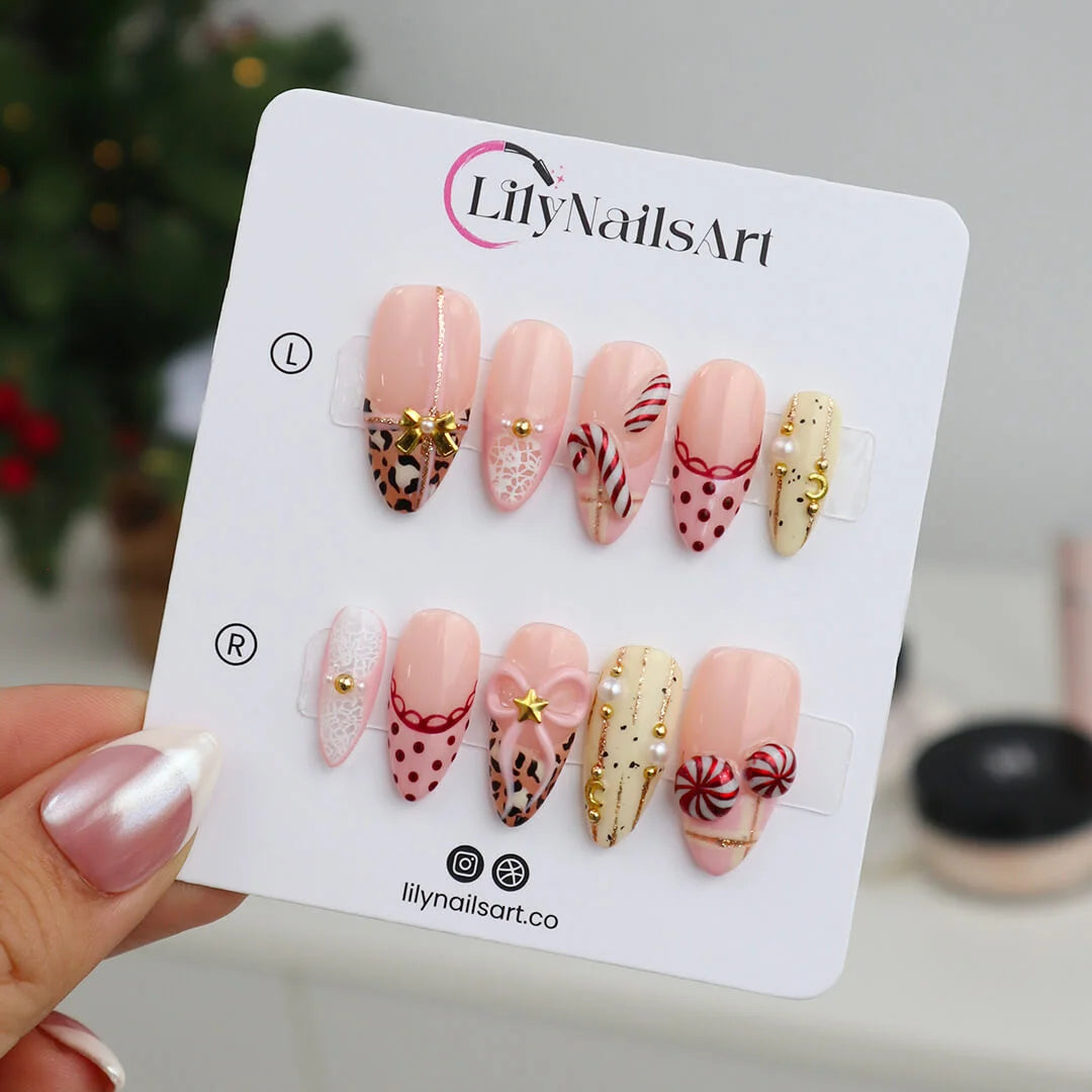 3D pink leopard print press on nails with red candy cane, gold bow, and peppermint swirl accents — handmade Christmas 2025 nails, festive fake nails, holiday nail art