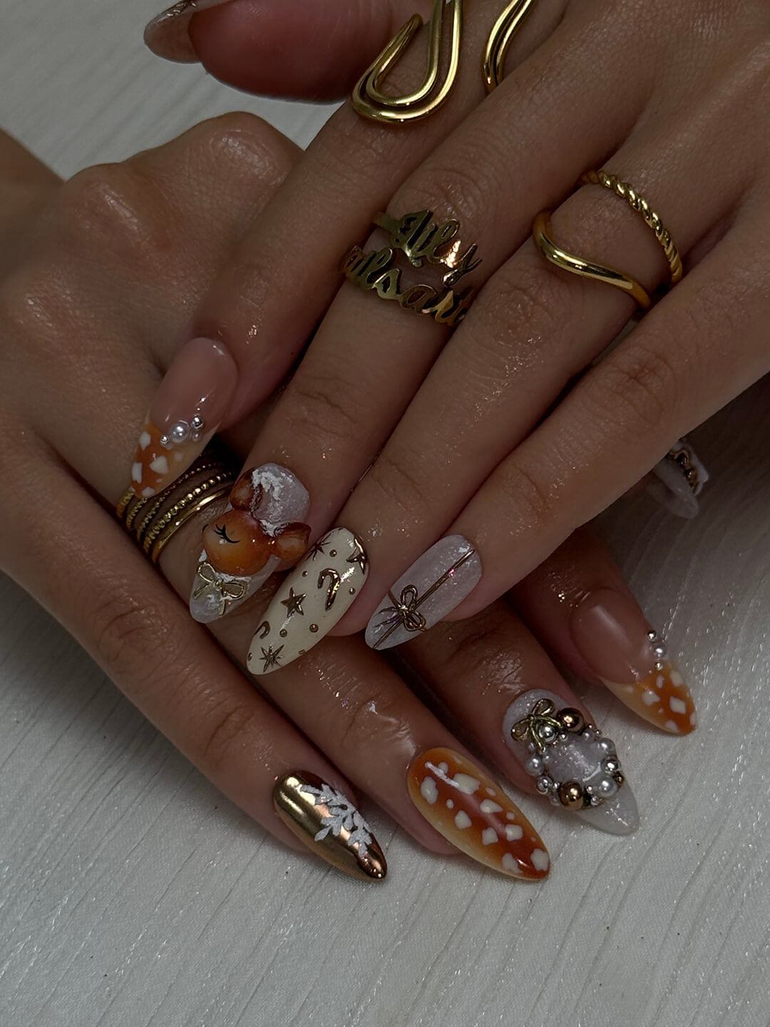 3D holiday press on nails in nude, caramel, and white with reindeer art, candy cane swirls, Christmas tree charms, metallic gold details — luxury handmade Christmas nails, reusable false nails, festive nail art — perfect for winter parties, holiday gifts, or cozy glam nights.