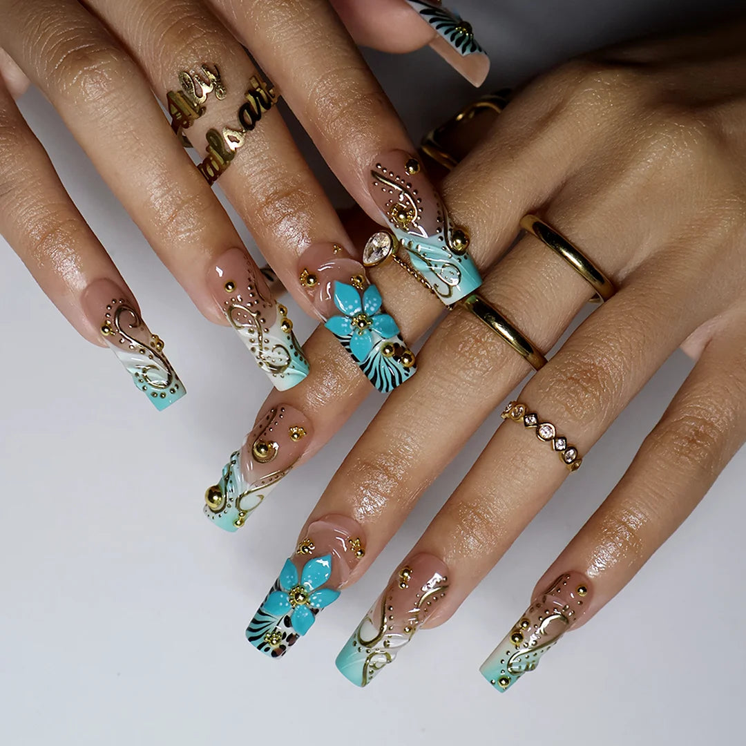 hand model wearing Vermentino handmade press-on nails — maximalist long square set in Tiffany blue with 3D turquoise lilies, gold swirls and leopard print
