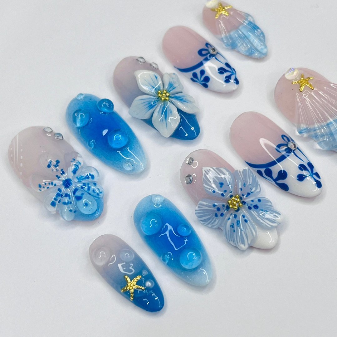 3D blue press on nails with ocean waves, starfish, seashells, and floral accents — luxury handmade summer nails for beach days and vacations.