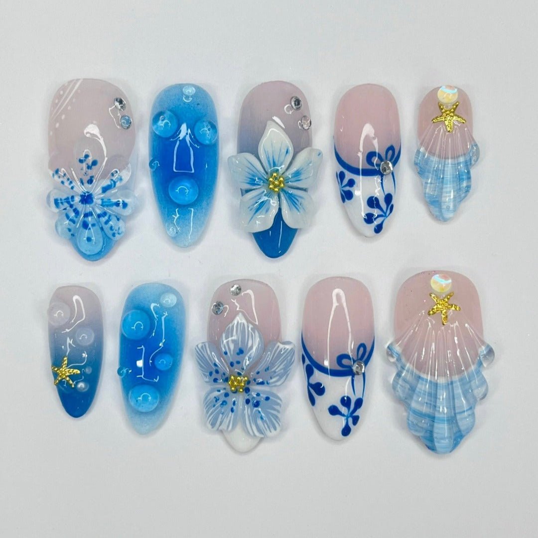 3D blue press on nails with ocean waves, starfish, seashells, and floral accents — luxury handmade summer nails for beach days and vacations.