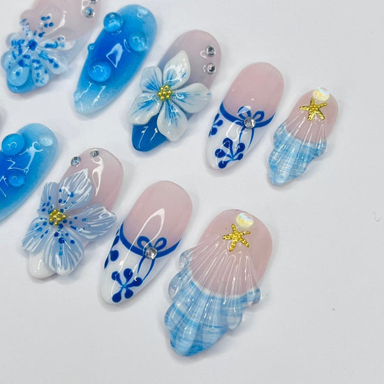 3D blue press on nails with ocean waves, starfish, seashells, and floral accents — luxury handmade summer nails for beach days and vacations.