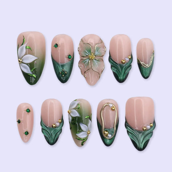 3D emerald green press on nails with white lily florals and gold vine accents, embellished with emerald crystals, pearls, and gold chain details on a nude base — custom press on nails, luxury handmade nail art, fake nails, false nails, pressons — perfect for prom, galas, and emerald-themed events