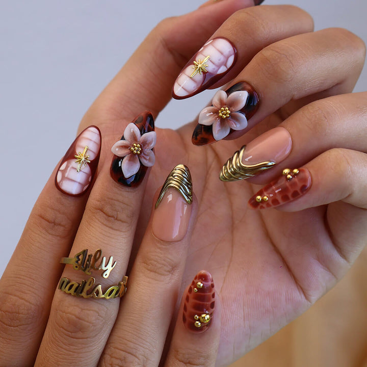 Luxury press-on nails with tortoiseshell patterns, 3D florals, and gold metallic accents on warm amber and nude bases — handmade medium almond nails — perfect for elegant everyday wear, chic autumn looks, or timeless luxury nail art.