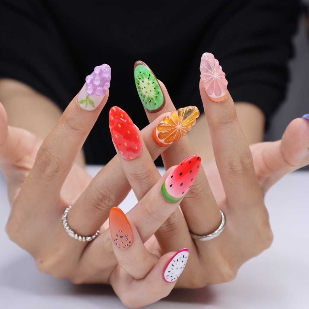 a hand model wearing 3D fruit press on nails with realistic designs of cherry, grapefruit, kiwi, strawberry, papaya, dragon fruit, watermelon, orange slice, grapes, and blueberries — custom press on nails, luxury handmade nail art, fake nails, false nails, pressons — perfect for summer vibes, fruity themes holiday, vacation ,or a fun gift for her.