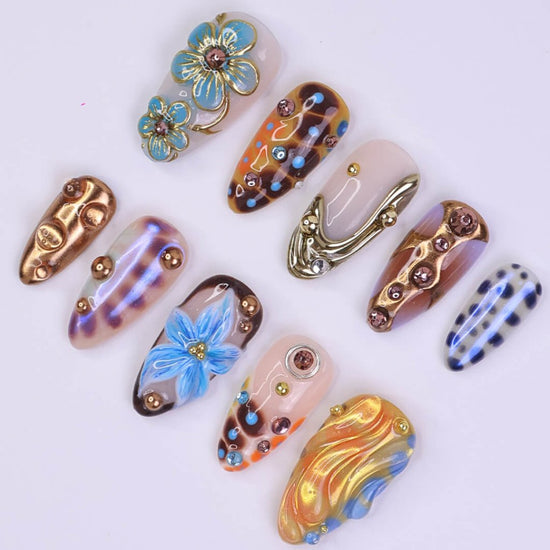 Metallic blue press on nails with sculpted floral accents and bronze chrome — custom almond shape for summer or Y2K looks

