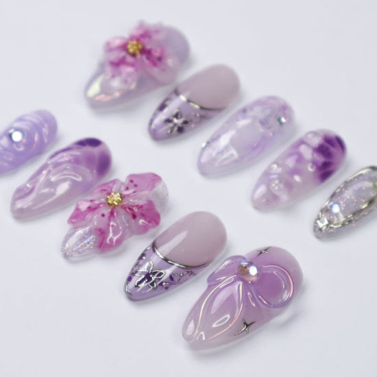 3D purple and lavender press on nails with butterfly art, pink sakura flowers, glossy swirls, and crystal bow charms — custom press on nails, luxury handmade nail art, fake nails, false nails, pressons — perfect for spring, summer, romantic gifts, or soft aesthetic lovers