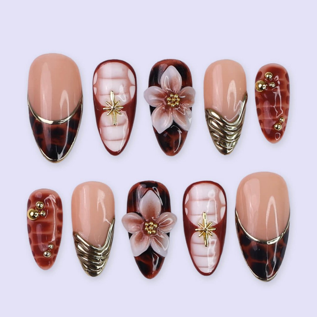 Luxury press-on nails with tortoiseshell patterns, 3D florals, and gold metallic accents on warm amber and nude bases — handmade medium almond nails — perfect for elegant everyday wear, chic autumn looks, or timeless luxury nail art.