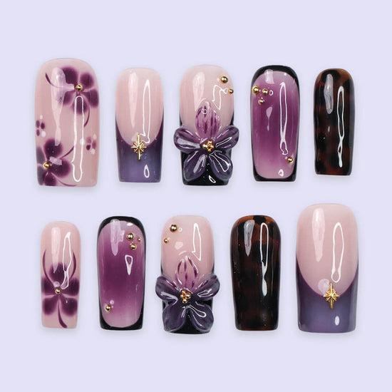 Handmade press-on nails in medium square shape featuring nude base, purple ombre, tortoise accents, and 3D orchid floral design with gold embellishments