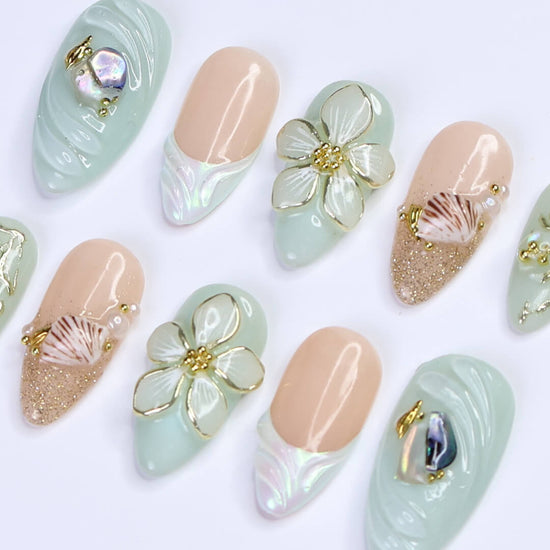 3D seafoam press-on nails with pearl flower accents, gold seashells, and iridescent wave textures — handmade luxury nail art, reusable and custom-sized false nails in a soft pastel green and nude colorway — perfect for beach weddings, summer travel, or romantic coastal looks.