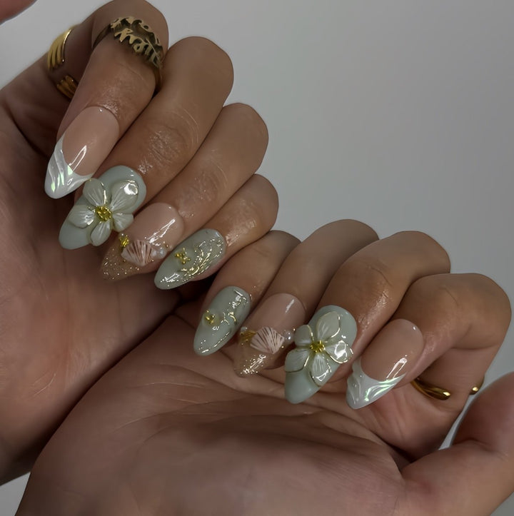 3D seafoam press-on nails with pearl flower accents, gold seashells, and iridescent wave textures — handmade luxury nail art, reusable and custom-sized false nails in a soft pastel green and nude colorway — perfect for beach weddings, summer travel, or romantic coastal looks.