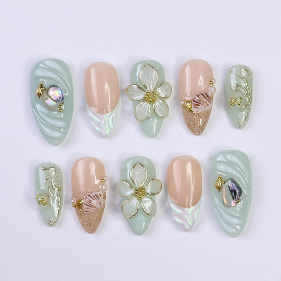 3D seafoam press-on nails with pearl flower accents, gold seashells, and iridescent wave textures — handmade luxury nail art, reusable and custom-sized false nails in a soft pastel green and nude colorway — perfect for beach weddings, summer travel, or romantic coastal looks.