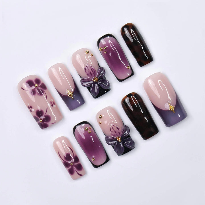 Handmade press-on nails in medium square shape featuring nude base, purple ombre, tortoise accents, and 3D orchid floral design with gold embellishments