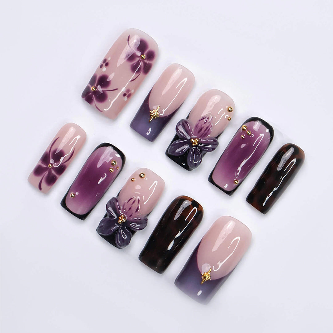 Handmade press-on nails in medium square shape featuring nude base, purple ombre, tortoise accents, and 3D orchid floral design with gold embellishments
