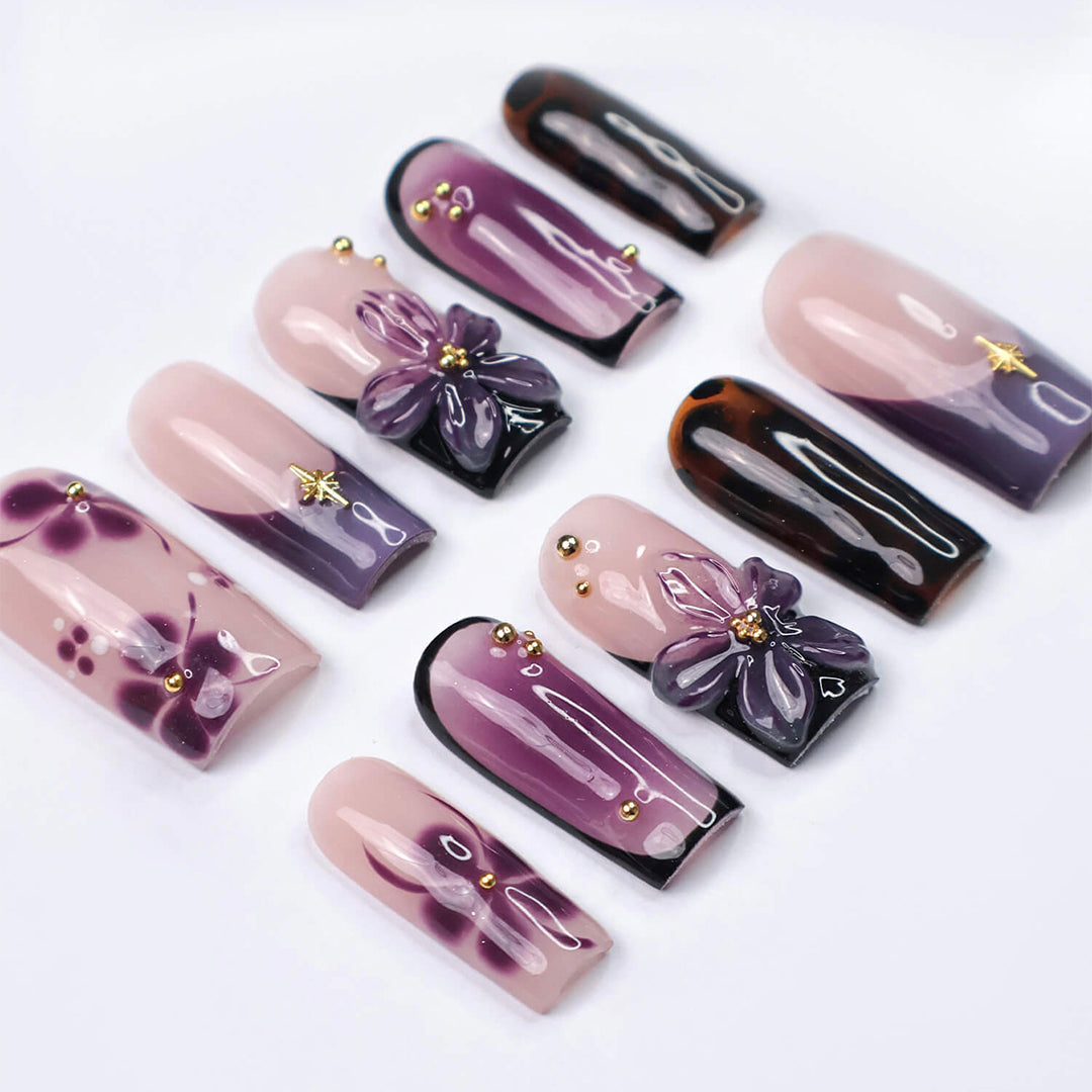Handmade press-on nails in medium square shape featuring nude base, purple ombre, tortoise accents, and 3D orchid floral design with gold embellishments
