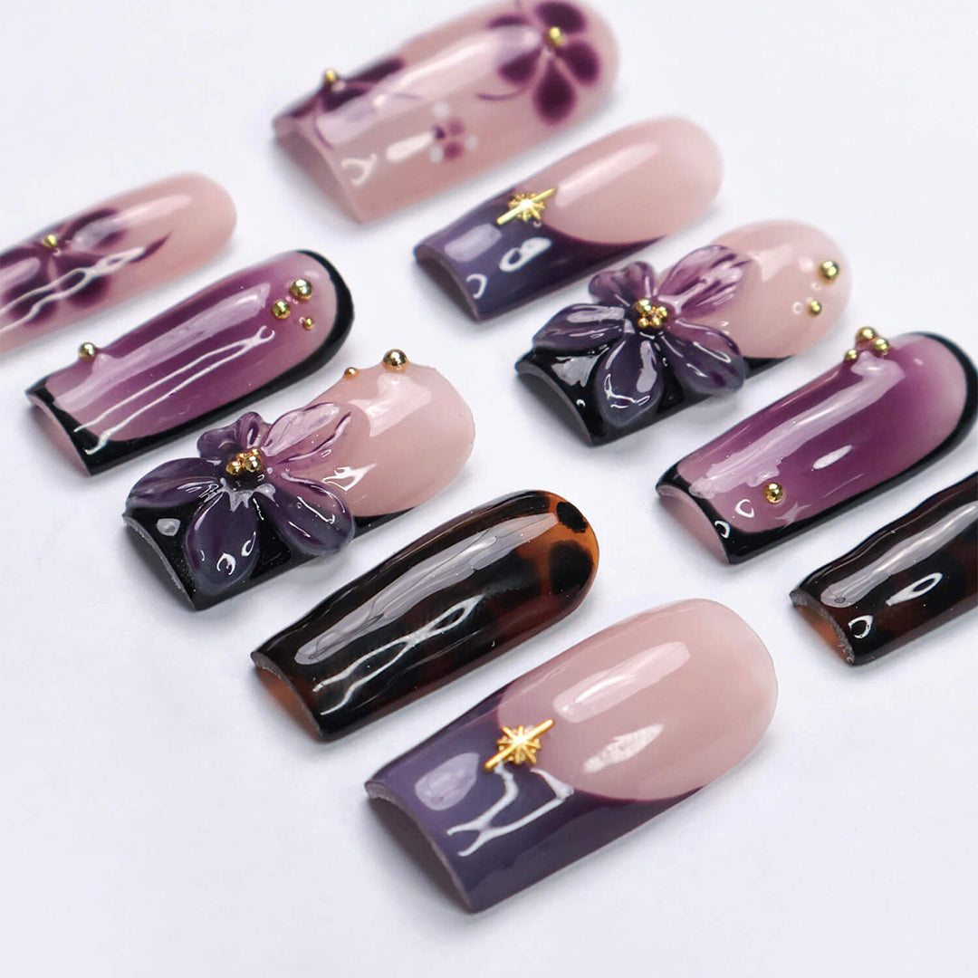Handmade press-on nails in medium square shape featuring nude base, purple ombre, tortoise accents, and 3D orchid floral design with gold embellishments