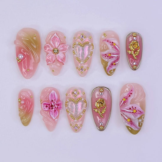 3D pink press on nails with floral and heart designs, embellished with gold studs, glitter accents, and hand-shaped lily flowers — custom press on nails, luxury handmade nail art, fake nails, false nails, pressons — perfect for spring, weddings, holidays, birthdays, or a thoughtful gift for her.