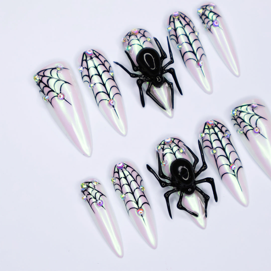 White chrome stiletto Halloween press on nails with 3D black spiders, spiderweb line art, and iridescent crystal accents — handmade spooky press-ons, custom fake nails for Halloween parties, creepy cute nail art, horror fashion aesthetic.