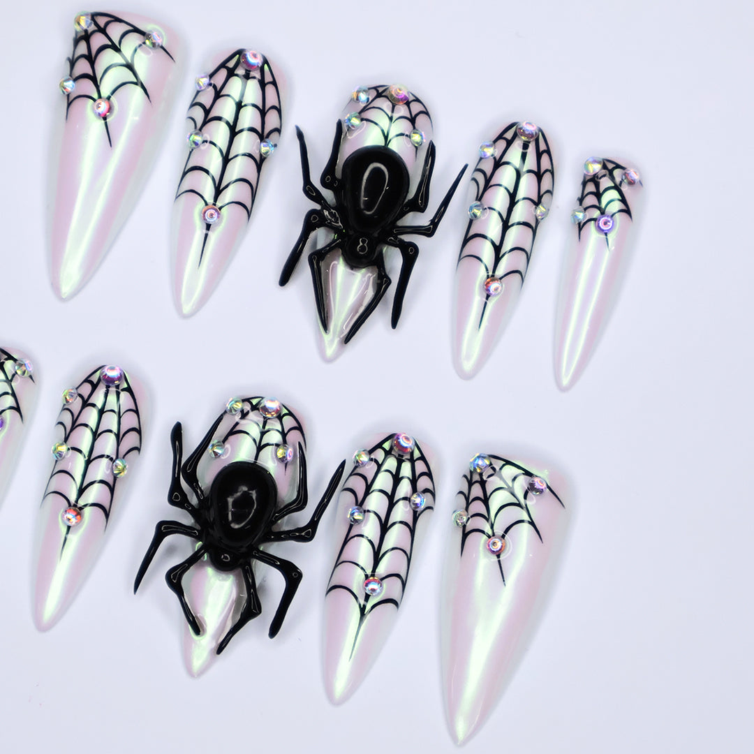 White chrome stiletto Halloween press on nails with 3D black spiders, spiderweb line art, and iridescent crystal accents — handmade spooky press-ons, custom fake nails for Halloween parties, creepy cute nail art, horror fashion aesthetic.