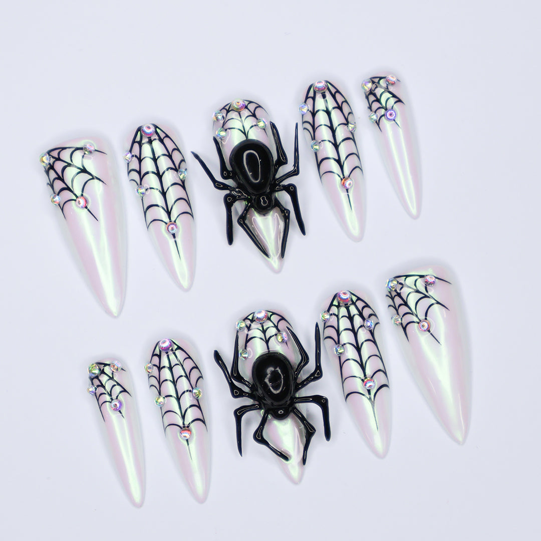 White chrome stiletto Halloween press on nails with 3D black spiders, spiderweb line art, and iridescent crystal accents — handmade spooky press-ons, custom fake nails for Halloween parties, creepy cute nail art, horror fashion aesthetic.
