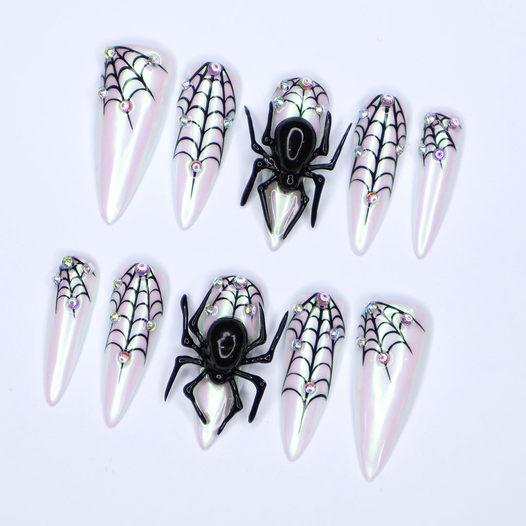 White chrome stiletto Halloween press on nails with 3D black spiders, spiderweb line art, and iridescent crystal accents — handmade spooky press-ons, custom fake nails for Halloween parties, creepy cute nail art, horror fashion aesthetic.