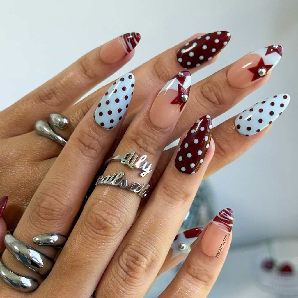 Handmade almond press on nails featuring a playful mix of burgundy polka dots, nude base with burgundy geometric tips, silver bead accents, and abstract line art. Retro-inspired, perfect for a bold and stylish look.
