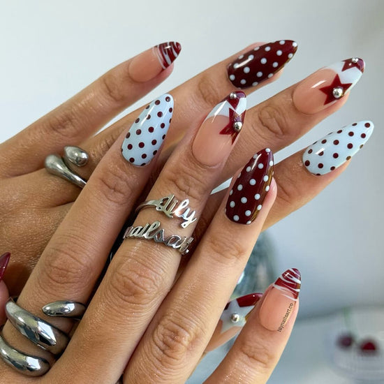 Handmade almond press on nails featuring a playful mix of burgundy polka dots, nude base with burgundy geometric tips, silver bead accents, and abstract line art. Retro-inspired, perfect for a bold and stylish look.