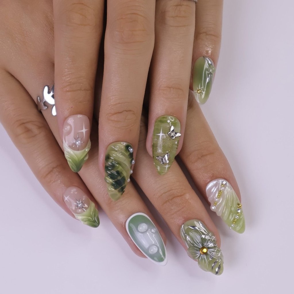 Awaken the spirit of the forest with Sylvara, a graceful press-on nail set woven with misty greens, sparkling silver details, and sculpted 3D florals. Blending soft gradients, leafy textures, and dewdrop-like accents, Sylvara captures the quiet magic of nature’s hidden groves. 🌿
