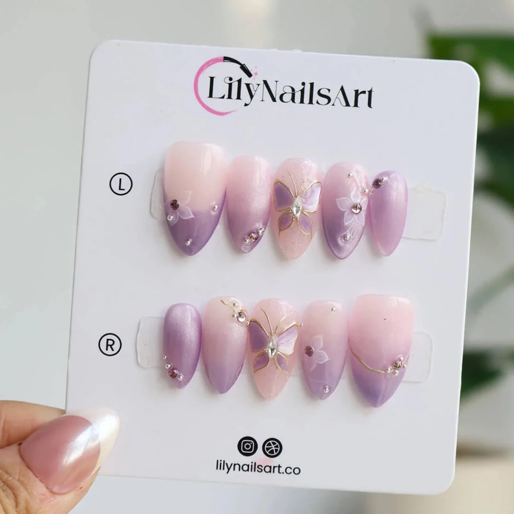 3D lavender ombré press on nails with gold butterfly motif, embellished with white floral accents and crystals — custom press on nails, luxury handmade nail art, fake nails, false nails, pressons — perfect for prom, spring events, and fairy-tale aesthetics